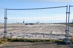 Vor dem Bauzaun der JadeWeserPort-Baustelle in Wilhelmshaven